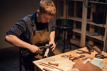 a young master in the manual production of shoes in his workshop is working on creating shoes