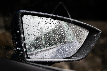 Car side view mirror covered in rain drops