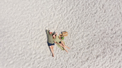 Aerial view of a young couple lying on the white sand. man and woman spend time together and travel...