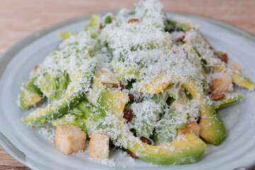 Chicken salad with avocado, bacon and cheese in a white plate on wooden table. Healthy salad bowl with chicken, avocado, mixed greens and cheese. Chicken salad with avocado and bacon. Food and health.