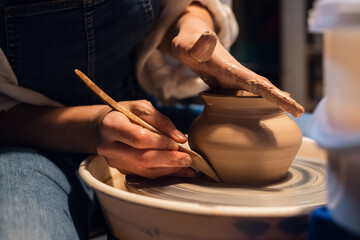 beautiful hands of a young girl potter in the process of sculpting a vase with clay and tools