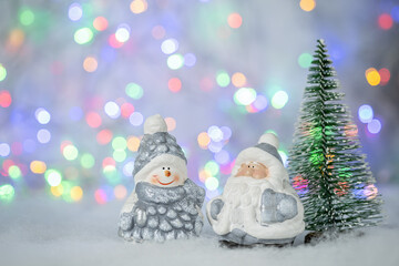 Christmas greeting card with decorative cute snowman, Santa Claus and green fir tree. Bokeh effect on background