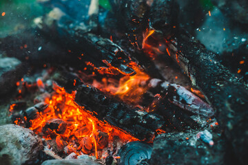 Vivid smoldered firewoods burned in fire closeup. Atmospheric background with orange flame of...