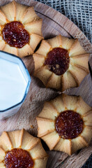 Kurabye cookies with filling on a wooden plate in a circle around a glass of milk.