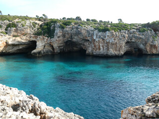 fotografia tomada en verano del 2020 en la playa de cala varques de de mallorca. en la fotografia unas cuevas naturales en la costa
