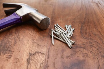 WIP or work in progress concept.  A hammer and a group of nails isolated on the wooden background 