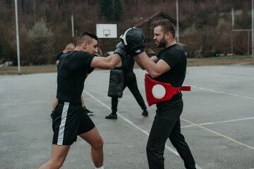Two athletic young men boxing . Men training outdoors . Training kickboxing.Two males boxing outdoors. Sparring training box outside sport concept.