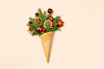 Waffle cone with branches of a Christmas tree and toys on a yellow background. The concept photo is an original New Year's gift.