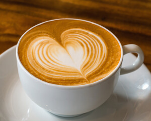 Cup of coffee with latte art on wooden background