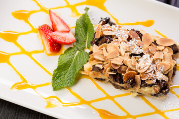 chocolate cake with creamy stuffing, garnished with planed almonds, mint and strawberries