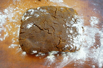 Brown gingerbread cookie dough with flour on a silicone mat