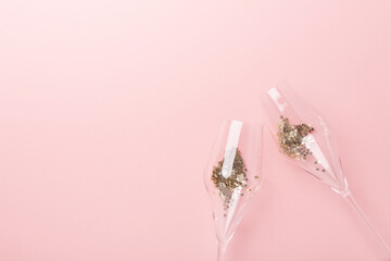 Christmas flat lay. Champagne glasses and gold decoration on pink background