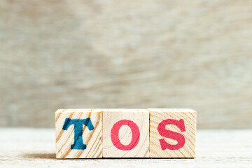 Alphabet letter block in word TOS (abbreviation of Terms of service) on wood background