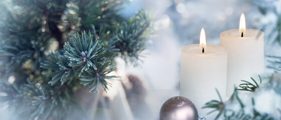 Candles with fir branches in the winter sunlight. Frozen christmas decoration with festive bokeh. Background with short depth of field for christmas and advent concepts with space for text.
