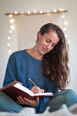 Woman in blue sweater making notes in her journal