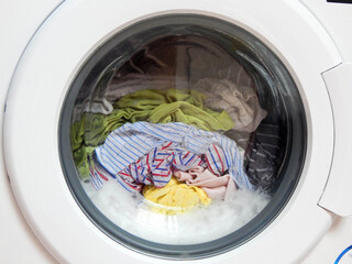 Foamy washing machine with different clothes.