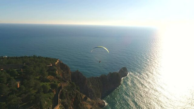 Parachute jumper is flying over Taurus Mountains range overwashed by Mediterranean sea in sunny Alanya, Antalya Province in Turkey. Beautiful nature footage from copter.