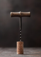 Wine cork with vintage corkscrew on top on wood background. - obrazy, fototapety, plakaty