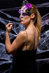 Naklejka premium Woman dressed in elegant way as witch for Halloween party with black background and spider webs