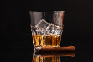 Burning cigar and glass of whisky on black background