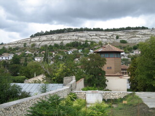 A small village among hills and forests on a cloudy gray day. Low houses merge into a landscape of...