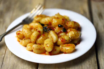 Gnocchi in chili tomato sauce on a white plate.