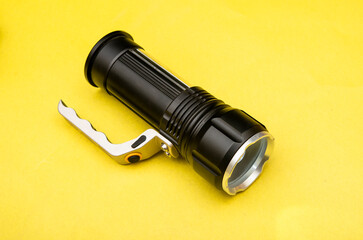 Black Flashlight on yellow table banner top view