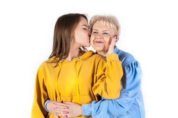 Young daughter kissing her elderly mother on white background. Loving family