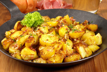Classic Roasted Potatoes in a Pan with Bacon and Onions on wooden Background