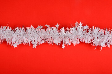 Red background with white Christmas garland and small stars. Christmas background, copy space, Christmas decorations