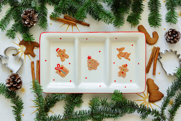 A plate with a Christmas pattern on a table with New Year's decor. Christmas tree and cookie cutter...
