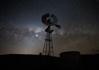 Wide Angle view of a Windpomp/Windmill in the Tankwa Karoo of South africa with a very bright milky way in the sky