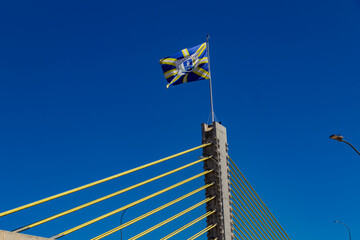 Viaduto Estaiado na cidade de An&aacute;polis em Goi&aacute;s. Viaduto com uma bandeira da cidade de An&aacute;polis com c&eacute;u azul ao fundo.
