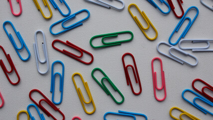 View from above. Colored paper clips on a white background, office