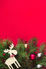 Christmas background, Christmas card. Festive wooden decorations, balls and spruce branches on a red background, top view, copy space