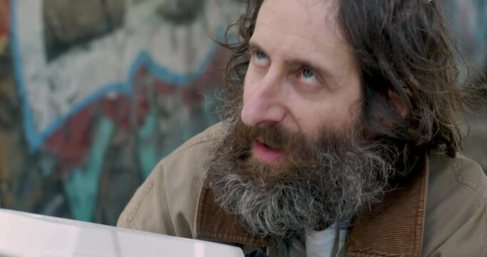 Close up of a homeless man eating food given to him by a stranger