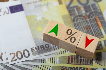 wooden cube block on stack of euro banknotes central banking system and change interest rates.
