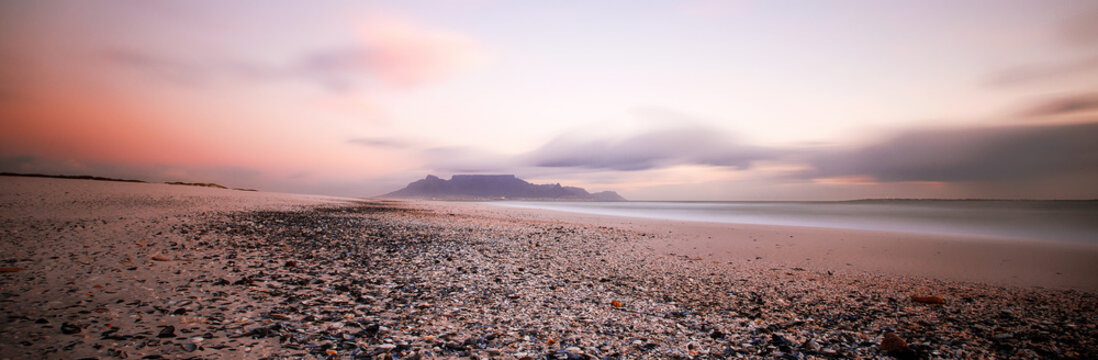 Wide angle view of Table Mountain, Cape Town South Africa from Blouberg Beach at Sunset with winter rainclouds moving by
