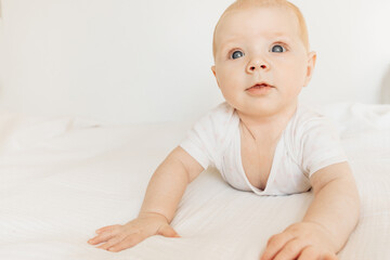 Portrait of adorable baby girl laying on comfortable bed at home, beautiful cute toddler look at the camera with big interest, childhood and childcare concept