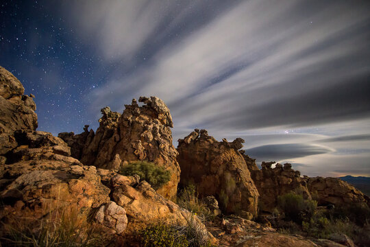 Wide Angle view of sandstone rock formations in the Southern Cederberg illuminated by the moonlight with spectacular clouds streaking by.