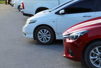 Closeup of front side of red car with  other cars parking in outdoor parking area.