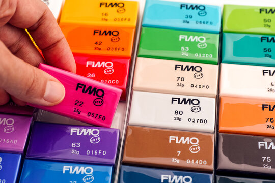 Tambov, Russian Federation - November 18, 2020 Woman hand taking crimson Fimo Soft modelling clay block from Fimo colour set