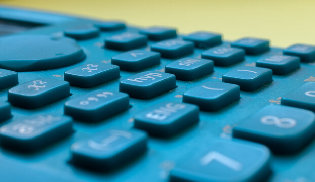 Close-up of a blue scientific calculator's buttons, over a blurred yellow background
