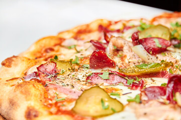 Fresh pizza pickles, bacon, sausages and cheese on a light background. Close-up, selective focus