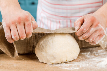 Making dough with men's hands on a wooden table.