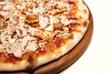Fresh pizza with bacon, tomatoes, mushrooms and cheese on a light background. Close-up, selective focus