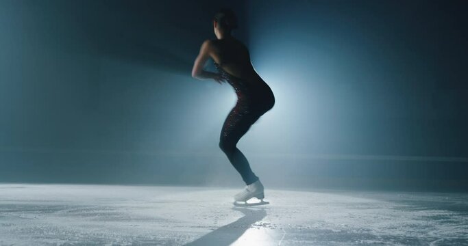 Cinematic shot of young female artistic figure skater is performing a woman's single skating choreography on ice rink before start of a competition. Concept of perfection, precision, freedom, passion.