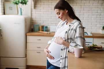 Pregnant happy nice woman smiling while having breakfast