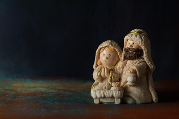 Representation of a Christmas nativity scene with the figures of baby Jesus, Mary and Joseph on a rock background. Phrase space on the left. Christmas concept.