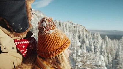 Young romantic couple in outerwear enjoying beautiful view from mountain peak and taking picture of nature with smartphone while hiking in national park on winter day